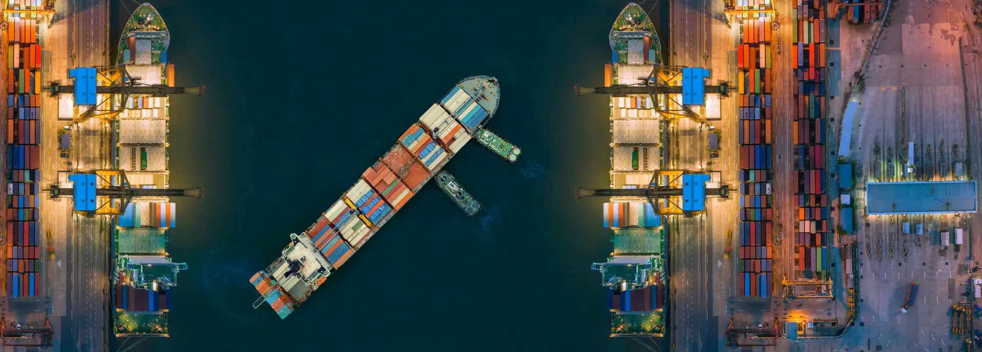Vue aérienne nocturne d'un porte-conteneurs accosté dans un terminal maritime, illustrant l'ampleur du transport maritime international